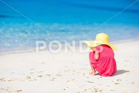 Adorable little girl drawing on white sand at the beach Stock Photos