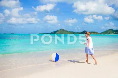 Adorable little girl playing with ball on beach. Kids summer sport outdoors on Stock Photos