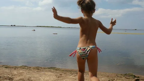An adorable little girl runs down the beach, to sea. Child playing outdoors Stock Footage 95335506