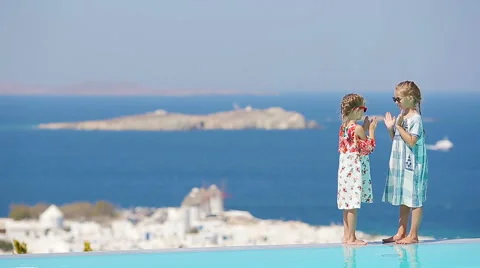 Adorable little girls playing in the edge of outdoor swimming pool with amazing Stock Footage