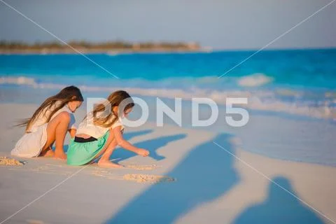 Adorable little kids having fun together drawing on the sand on white beach Stock Photos