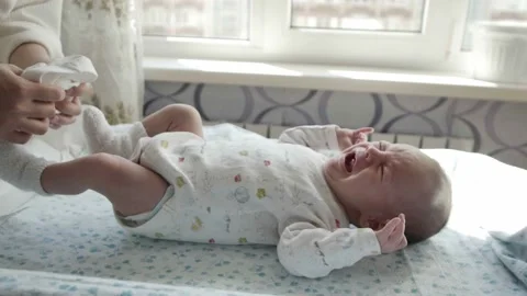 Adorable newborn baby crying while his mother dressing him Stock-Footage 89408620