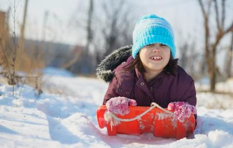 Adorable school aged kid girl in colorful sweater and hat playing in the snow Stock Photos