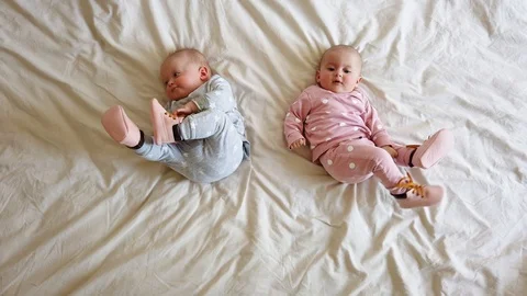 Adorable six months old baby twins in bed at home. Cute kids twins on bed. Stock Footage
