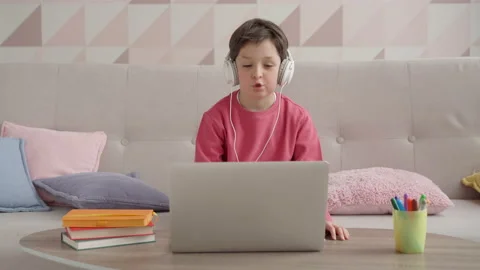 Adorable small child boy wearing headphones, looking at laptop camera, enjoying Stock Footage 154681067