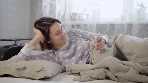 Adorable smiling brunette girl with short haircut dressed in grey pyjamas lying Stock Footage