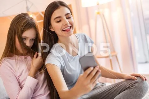 Adorable teenage girls goofing around while taking selfies Stock Photos