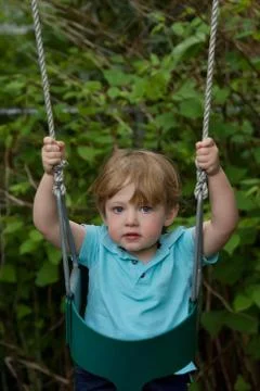 Adorable toddler boy playing on swing outside Stock Photos