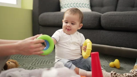 Adorable toddler playing with plastic hoops sitting on floor at home Stock-Footage 221026352