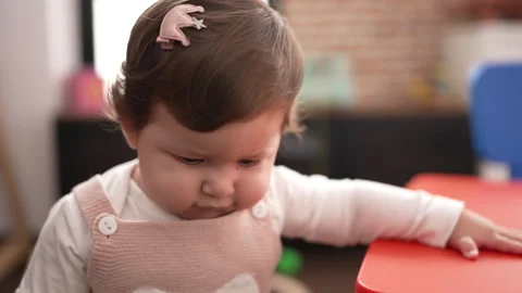 Adorable toddler standing with relaxed expression leaning on table at kinderg Video stock 221697359