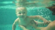 Adorable Toddler Is Swimming Under The Water In The Swimming Pool With Mom Stock Footage