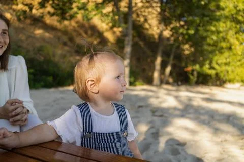 Adorable toddler with a tiny ponytail looking out at the beach on a sunny day Stock Photos