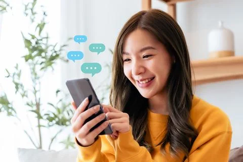 Adorable young Asian woman using mobile smartphone. Online live chat chatti.. Stock Photos