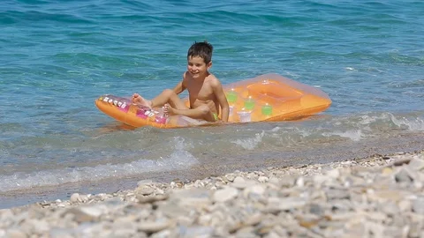 Adorable young boy playing on inflatable mattress at the beach. Kid enjoy in  Stock Footage 112256001