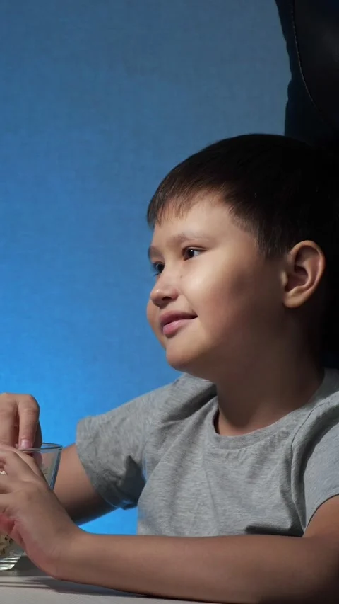 Adorable young boy smiling and laughing while enjoying popcorn as a snack at Video stock 340844425