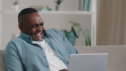 Adult african american man sitting looking at laptop screen puzzled worried Stock Footage