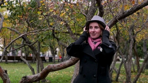 Adult beautiful woman in a hat walks in the autumn park. Joyful autumn walk Stock Footage