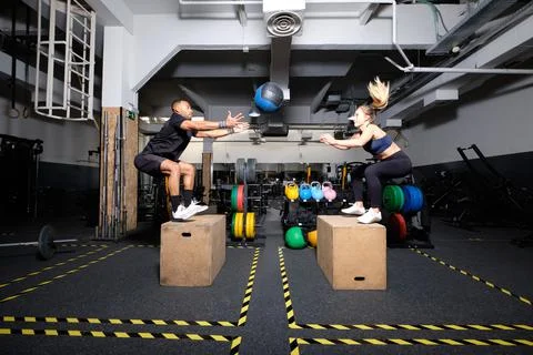 Adult couple jumping while trowing a medicine ball to each other Stock Photos