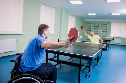 Adult disabled men in a wheelchair playing table tennis Stock Photos