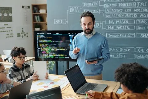 Adult Educator Explaining Programs to Young Students at School Stock Photos