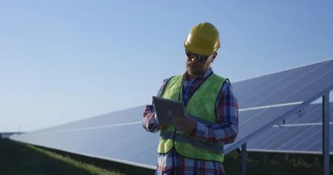 Adult engineer using tablet working among solar panels Foto stock