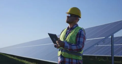 Adult engineer using tablet working among solar panels Stock Photos