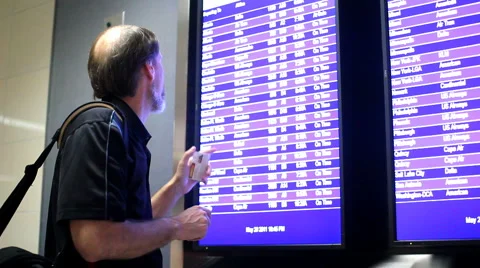 Adult male checking flight schedule at airport and then walking off. Stock Footage