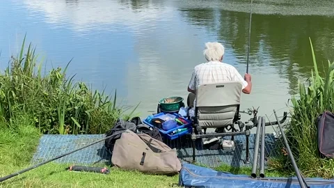 Adult male sitting fishing with equipment for catching fish ,sitting down Stock Footage