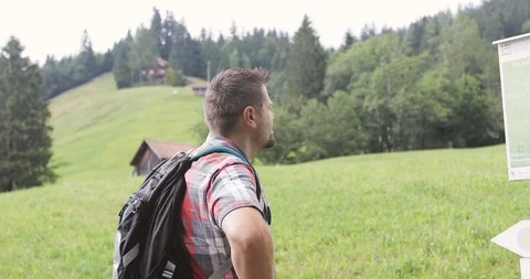 Adult man with a backpack reads pointers in the mountains. Video stock 103703801