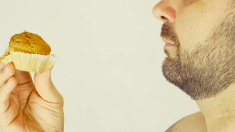 Adult man with bristles. He eats a little cupcake. Close-up. Stock Footage 107501202