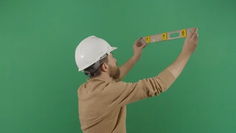 Adult man engineer using a level on green screen studio isolated shot against Vidéo 119663522