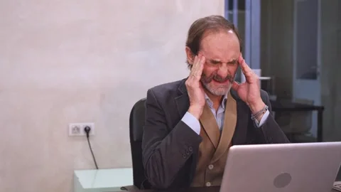 Adult man with headache while working on laptop in a modern office. Stock Footage 270046584