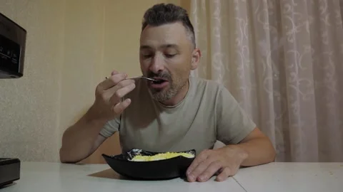 Adult man seated at dining table eating meal Stock Footage 341832845