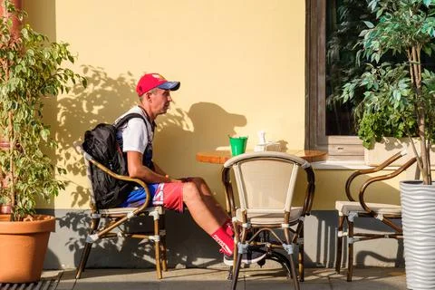 An adult man sits alone at a table in a street cafe Stock Photos