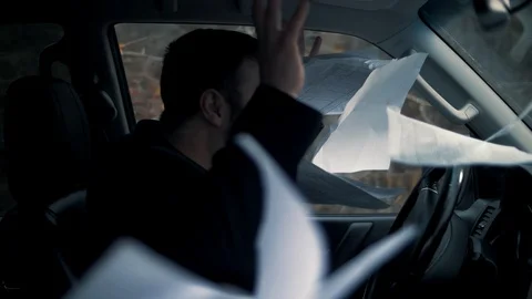 An adult man in a solid suit is psyche, scattering documents in the car Stock-Footage 102666651