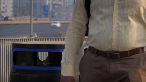 An adult man throws a empty plastic water bottle in pubic trash can or dust bin Stock Footage 325718915