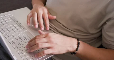 Adult man typing, tapping touchpad on sofa in tan shirt, black bracelet, working Stock Footage 342721652