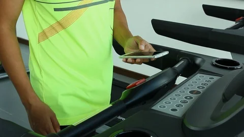 Adult man using smart phone during exercise, walking on treadmill, Lockdown. Stock Footage 105595341