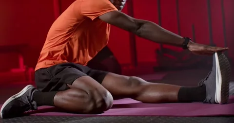Adult man warming up, stretching hamstring on purple mat at gym, reaching shoe Stock Footage 339958028