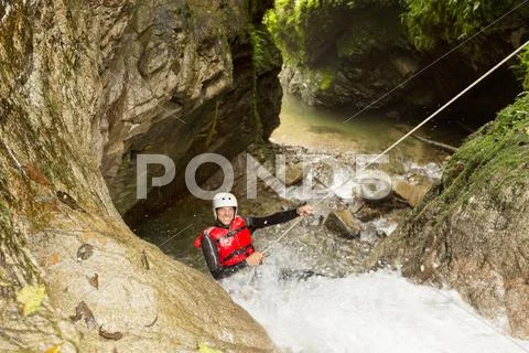 Adult Man Wearing Waterproof Equipment Descending A Waterfall Stock Photos