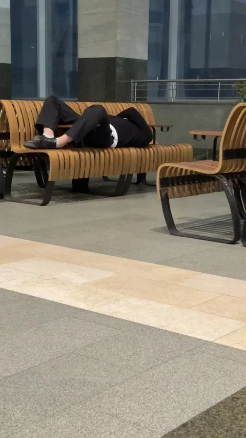 Adult Napping On Benches, Empty Transit Concourse, Curved Wooden Seating Stock Footage 325209052