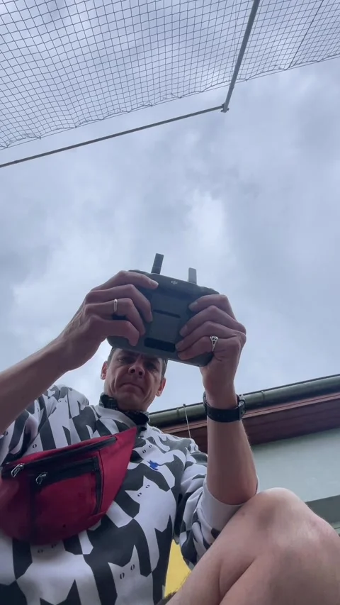 Adult operating drone remote control beneath overcast sky with steady focus now 库存影片 344584248