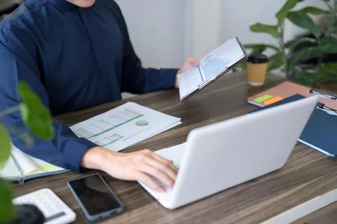 Adult professional reading notebook while working with laptop and reports o.. 스톡 사진