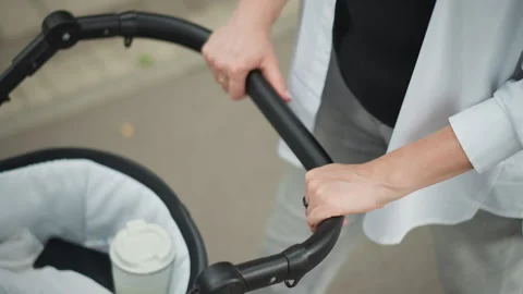 Adult steering stroller while multitasking in everyday urban environment. Parent Video stock 346380392
