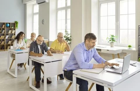 Adult students in computer training class with laptop in bright classroom Stock Photos