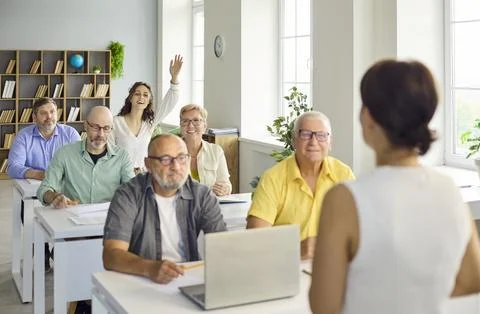 Adult students in computer training class, raising hands and engaging with Stock Photos