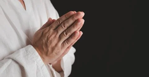 An adult whose hand is prayed on the dark background.Respect for belief in .. Stock Photos