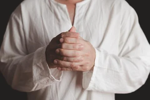 An adult whose hand is prayed on the dark background.Respect for belief in .. Stock Photos