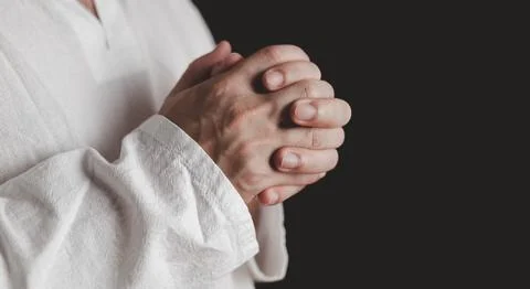 An adult whose hand is prayed on the dark background.Respect for belief in .. Stock Photos