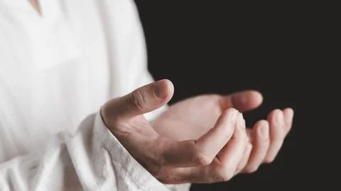 An adult whose hand is prayed on the dark background.Respect for belief in .. Stock Photos